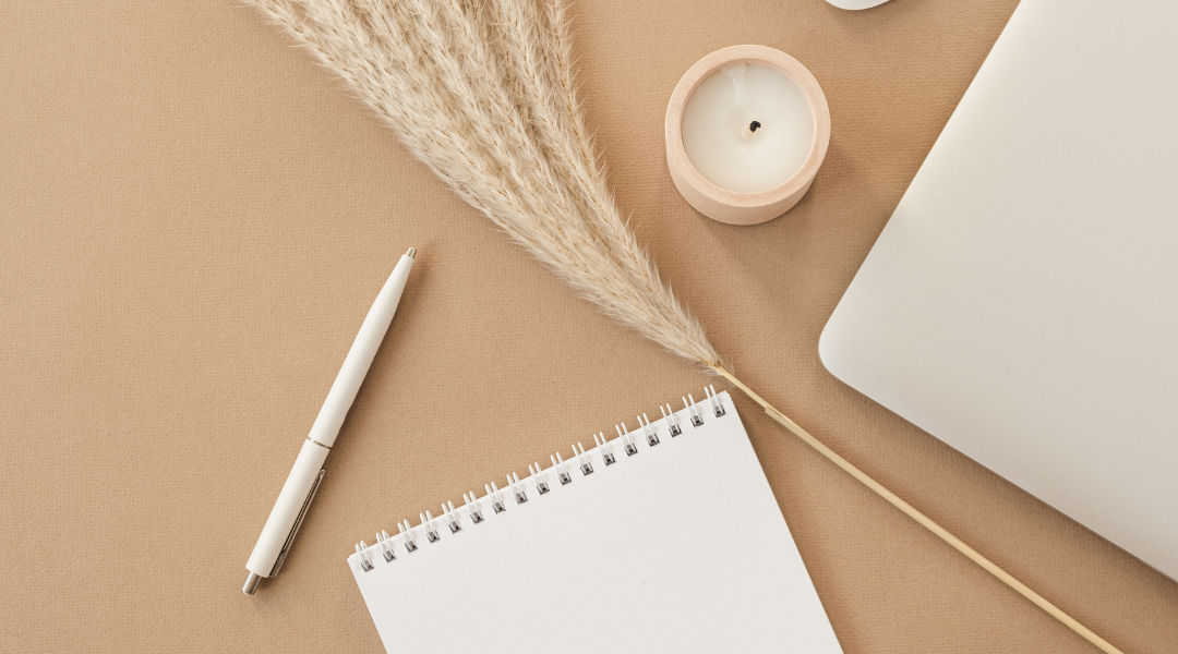 A notebook, pen, candle, and laptop sit on a desk. Sonrisa Studio shares how you can find and work with your dream clients.